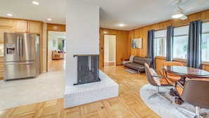 A modern kitchen with a built-in fireplace, wooden flooring, and a dining area with a round table and chairs. - 6 Mi to Dtwn: Waterfront Home in Tulsa! (Tulsa)