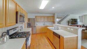 A spacious kitchen with wooden cabinets, a stainless steel refrigerator, a built-in stove, and a dishwasher. - 7 Mi to Downtown Baytown: Spacious Home w/ Yard (Baytown)