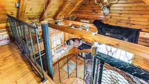 A wooden cabin with a loft bedroom featuring a bed, a wooden ceiling, and a kitchen area with a sink and stove. - 35 Mi to Acadia: Rustic Retreat in Orland! (Orland)