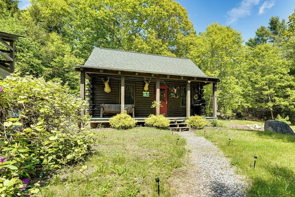 A rustic log cabin with a porch, surrounded by lush greenery and a gravel path. - 35 Mi to Acadia: Rustic Retreat in Orland! (Orland)