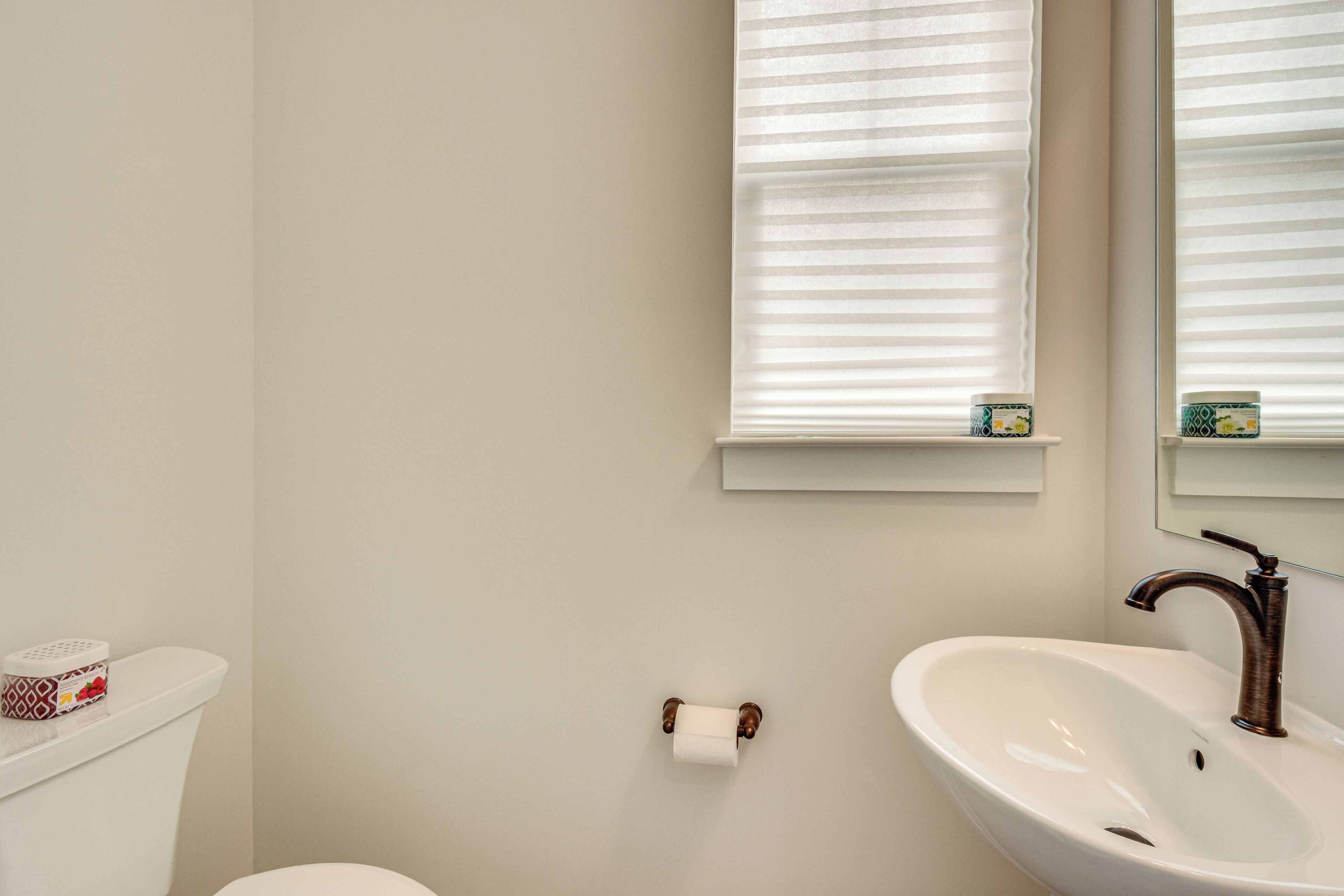 A bathroom with a toilet, a sink, and a window with blinds.