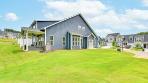 Een woonhuis met een overdekte veranda, een verzorgd gazon en een heldere lucht.