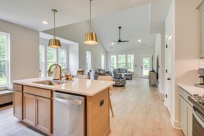 Una cocina amplia con una isla grande, armarios de madera e iluminación colgante.