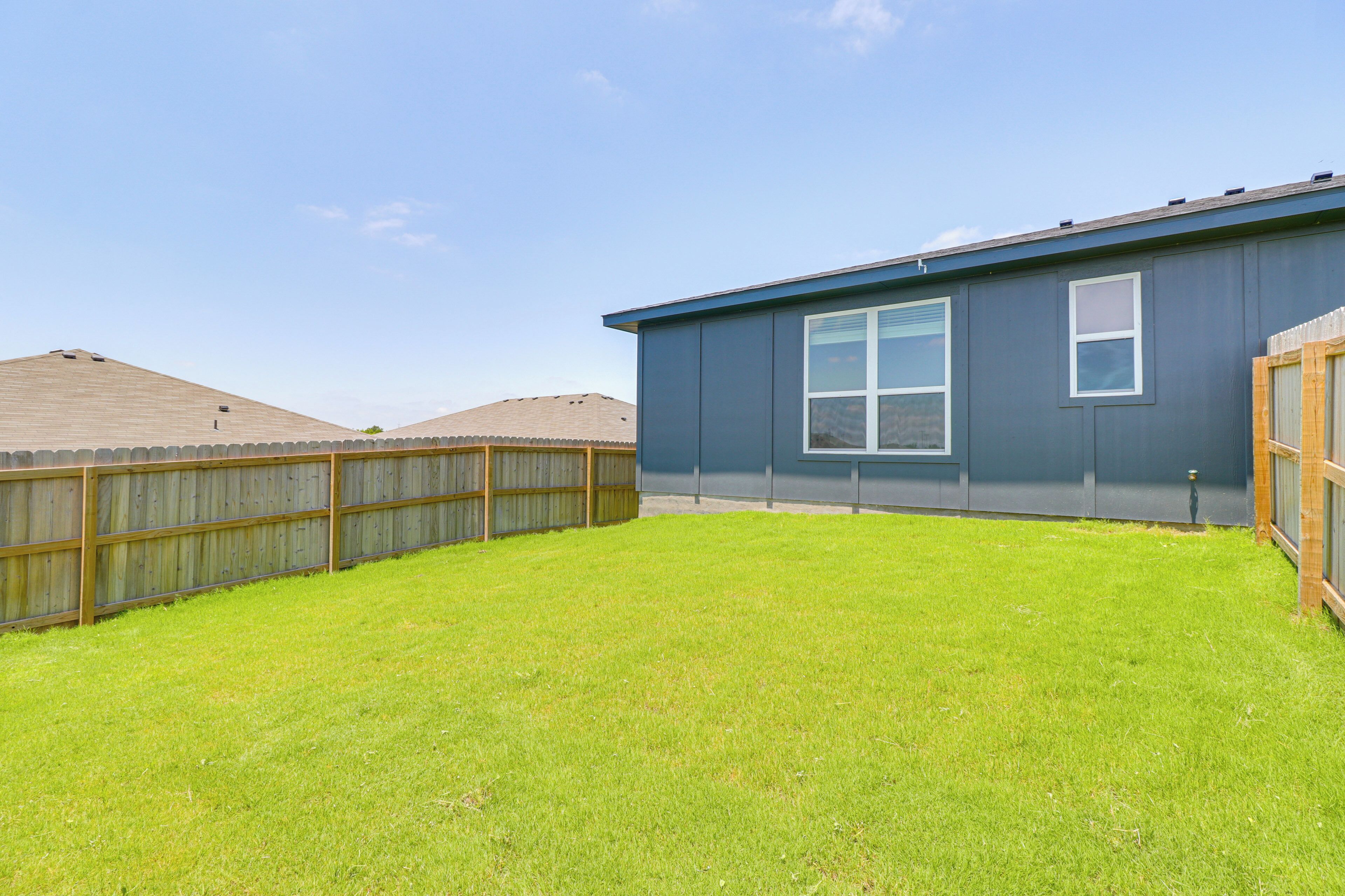 A residential building with a fenced backyard and a clear sky.