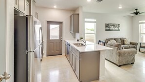 A modern kitchen with a built-in island, stainless steel appliances, and a neutral color palette. - 2 Mi to Dtwn Dining! Pet-friendly Temple Townhome (Temple)