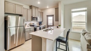 A modern kitchen with stainless steel appliances, a central island, and a window with blinds. - 2 Mi to Dtwn Dining! Pet-friendly Temple Townhome (Temple)