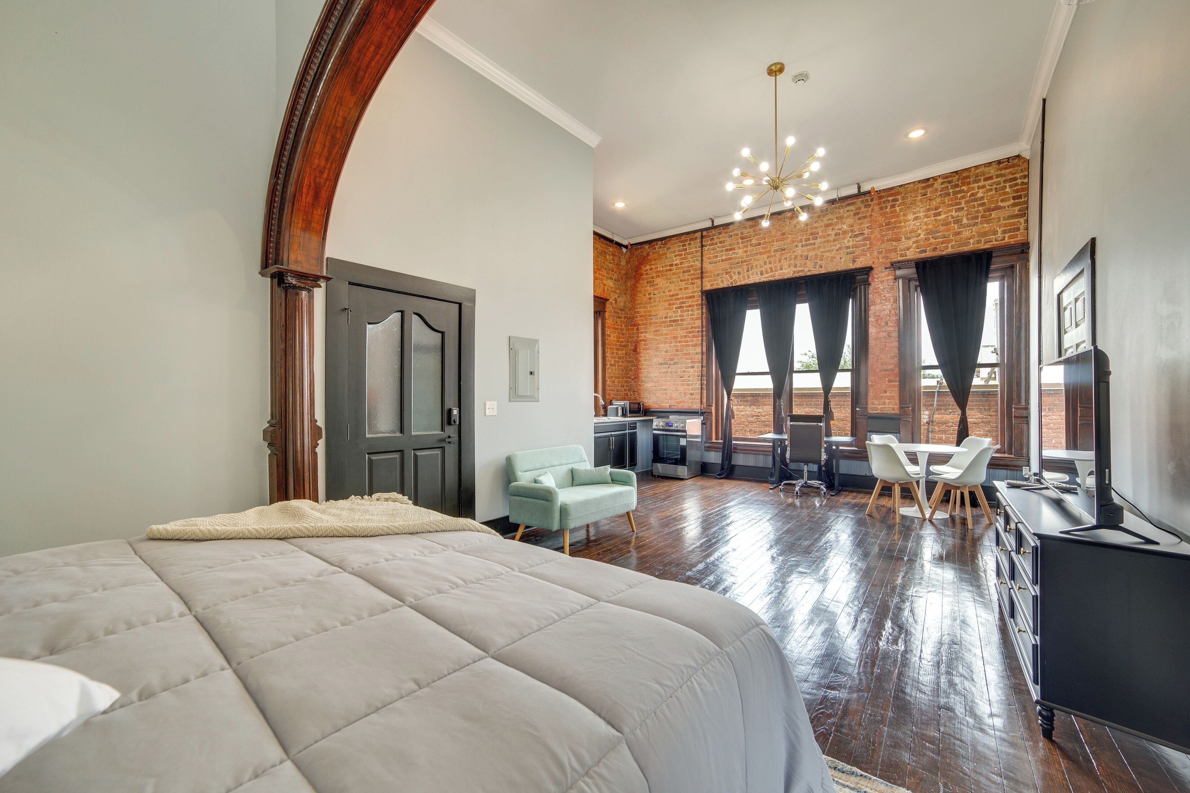 Une chambre d’hôtel moderne dotée d’un grand lit, d’une kitchenette, d’un coin repas et d’un mur en briques.