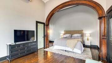A bedroom with a large bed, a TV, a dresser, and a wooden archway.