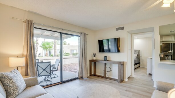 A modern living room with a sofa, a round coffee table, and a TV mounted on the wall. - Patio + Pool Access: Golf Getaway in Peoria (Peoria)