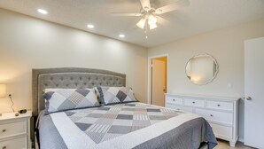 A bedroom with a bed, nightstands, a dresser, a ceiling fan, and a mirror. - Patio + Pool Access: Golf Getaway in Peoria (Peoria)