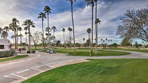 A golf course with palm trees, a parking lot, and a building in the background. - Patio + Pool Access: Golf Getaway in Peoria (Peoria)