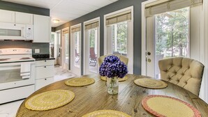 A kitchen with white cabinets, a microwave, and a stove. There is a dining table with placemats and a vase of flowers. - < 1 Mi to Marina: Fair Play Home on Lake Hartwell (Fair Play)