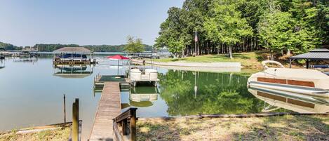 A calm lake with docked boats, a wooden pier, and a forested area.