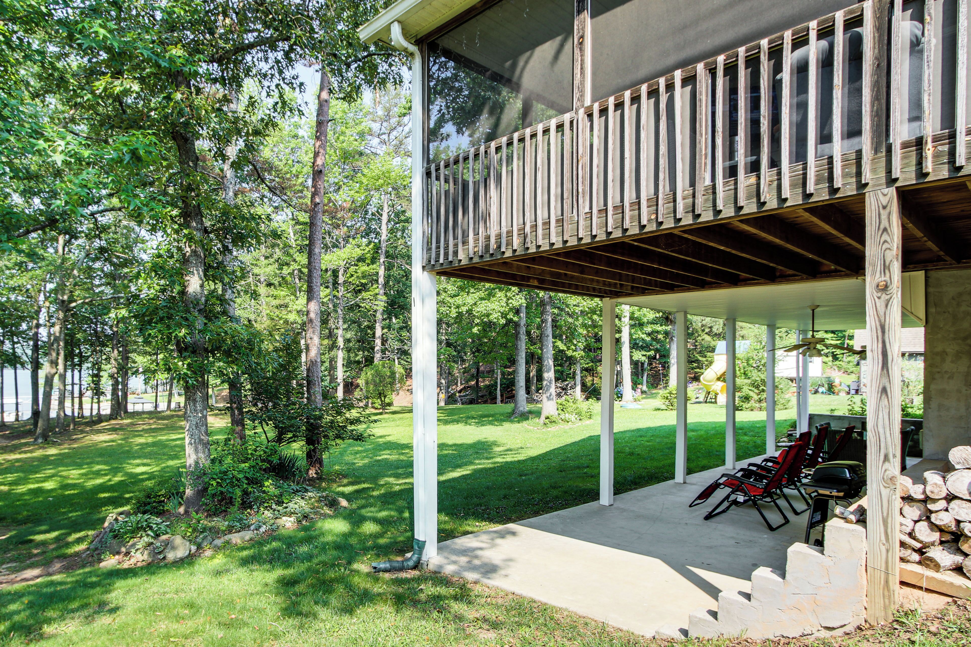 A covered outdoor area with a wooden deck, a grill, and a fire pit.