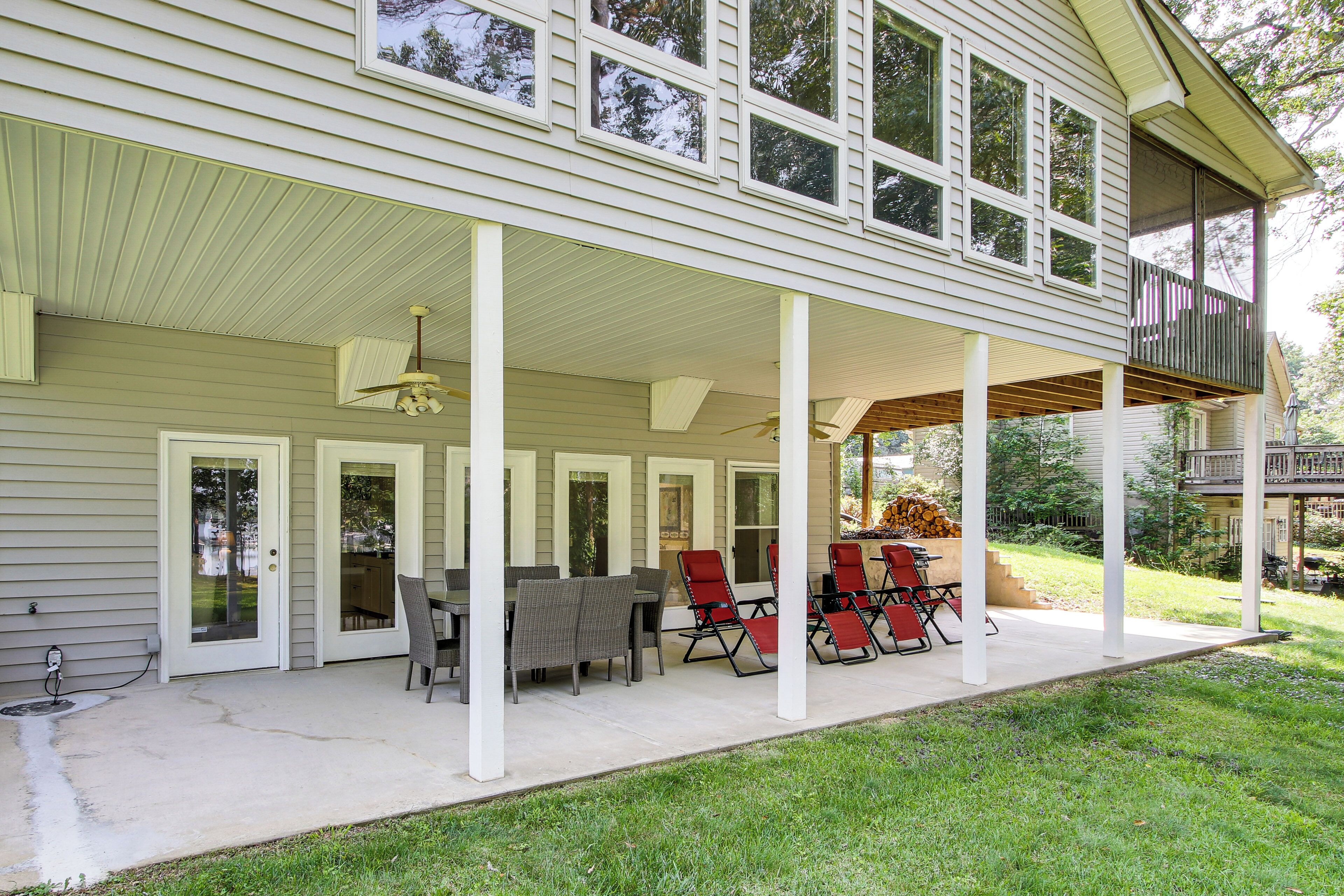 Une terrasse couverte avec une table et des chaises, un ventilateur de plafond et une vue sur le jardin arrière.