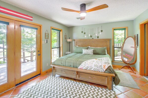 A bedroom with a large bed, wooden headboard, and a ceiling fan. - Secluded Lake Hamilton Access: Hot Springs Home (Hot Springs)