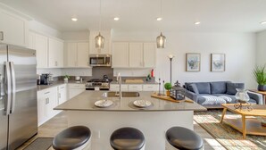 A modern kitchen with white cabinetry, stainless steel appliances, and pendant lighting.