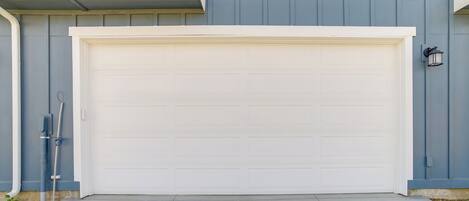 A garage door with a white garage door, a grey wall, and a small black outdoor light fixture.