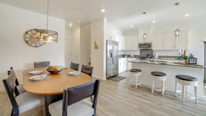 A modern kitchen with white cabinets, stainless steel appliances, and a wooden dining table with chairs. - Patio, Park & Peace: 'skyview Landing' in Eagle! (Eagle)