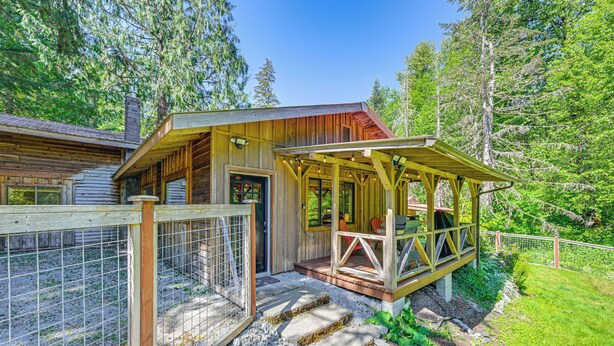 A wooden cabin with a covered porch and a fenced area. - 5 Mi to Mt Rainier Natl Park: Cozy Cabin w/ Deck! (Ashford)