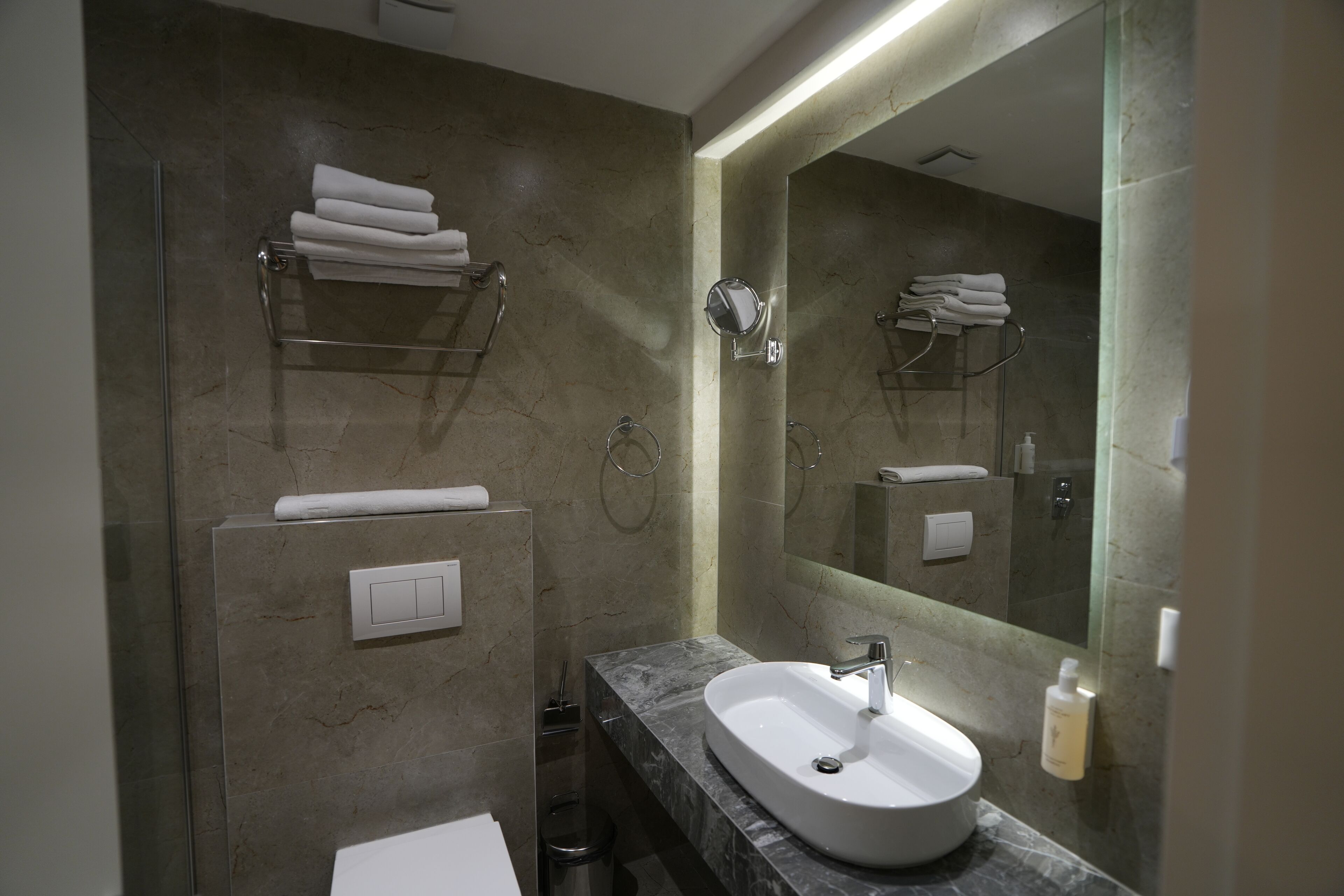 Une salle de bain moderne avec un lavabo en marbre, un grand miroir et des porte-serviettes.
