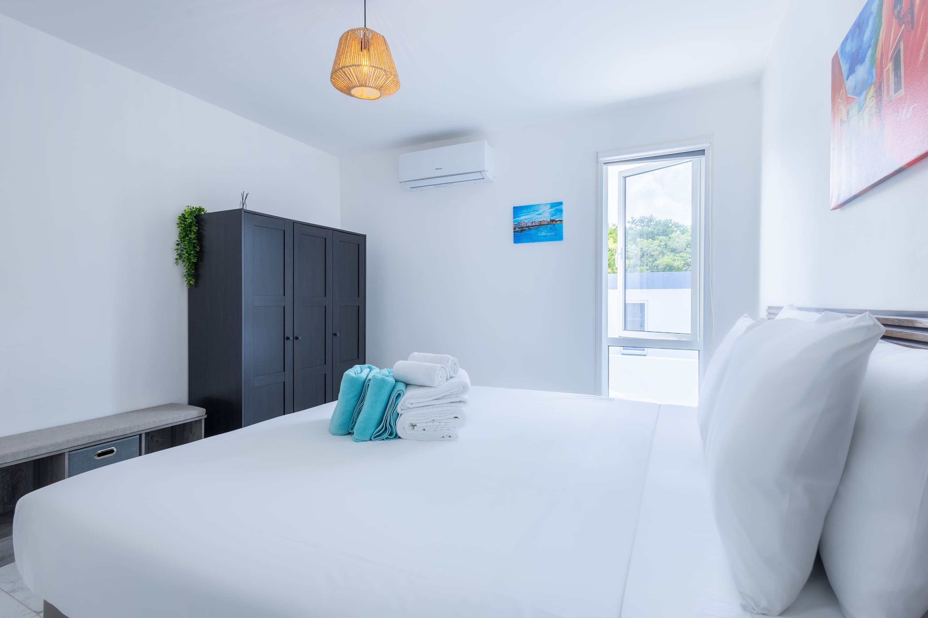 Une chambre d’hôtel moderne, dotée d’un grand lit, d’une armoire, d’un appareil de climatisation et offrant une vue par la fenêtre.