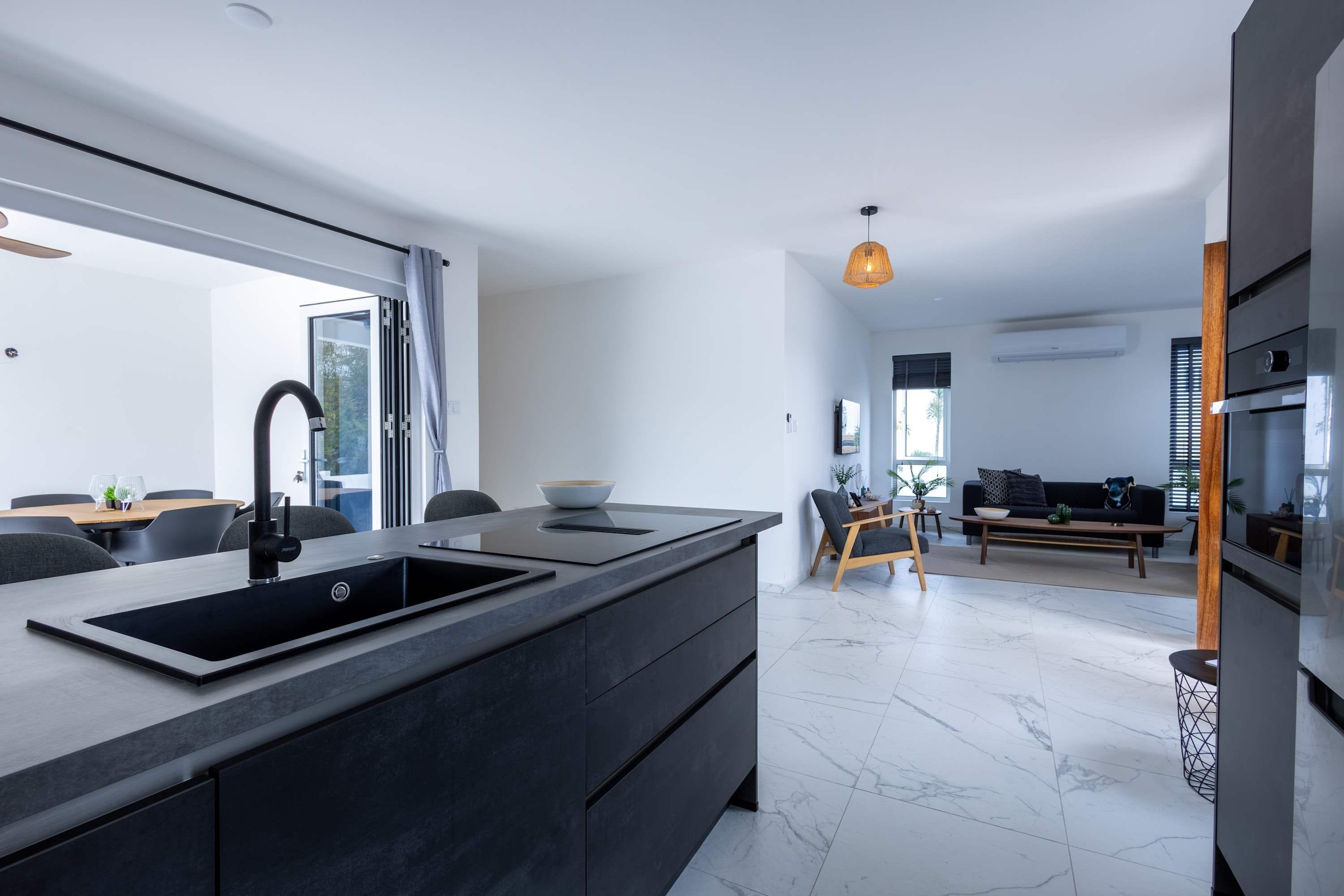 A modern kitchen with a large island, dark cabinetry, and a sleek black sink.