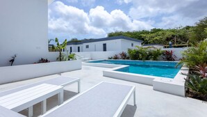 A modern outdoor pool area with white lounge chairs and a rectangular pool. - NEW Tropical Getaway With BBQ Pool (Jan Thiel)