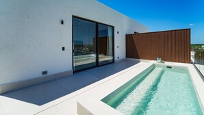 Un edificio moderno con piscina, puertas correderas de vidrio y valla de madera.