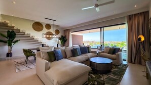 Una sala moderna con un sofá modular, una mesa de centro redonda y vistas de la ciudad.