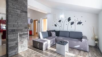 Ein modernes Wohnzimmer mit Ecksofa, Couchtisch und einer Wand mit floralen Dekorationen.