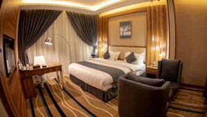 Una habitación de hotel con una cama grande, un escritorio, una silla y piso alfombrado.