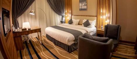Una habitación de hotel con una cama grande, un escritorio, una silla y piso alfombrado.