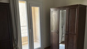 A bedroom with a bed, a wardrobe, and a sliding door leading to an outdoor area. - Spacious 3-Bd Hotel Apt in Gated Compound in Sheikh Zayed (Giza Governorate)