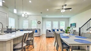 A spacious living area with a large island, seating arrangements, and a ceiling fan.
