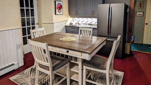 A compact kitchen with a dining table, chairs, and a refrigerator.