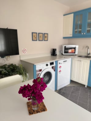 A kitchen with a washing machine, microwave, and cabinets. - Olea Alaçatı (Cesme)