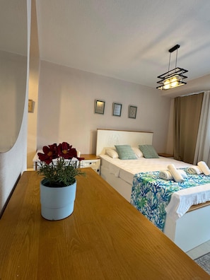 A hotel room with a bed, bedside table, potted plant, and a ceiling light fixture. - Olea Alaçatı (Cesme)