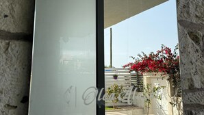 Un edificio moderno con una porta in vetro e vista su un giardino con fiori rossi.