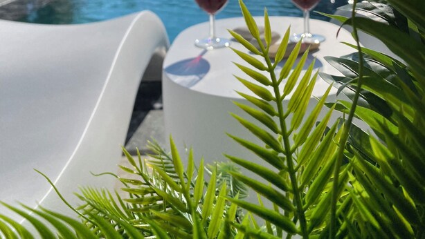 Zona piscina con lettini e un tavolo con due bicchieri da vino.