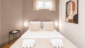 A bedroom with a bed, two bedside tables, a window with curtains, a wall-mounted artwork, and a small round table. - 1611 Vouillé (Paris)