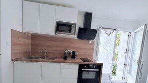 A modern kitchen with white cabinets, a wooden countertop, a built-in microwave, a coffee machine, and a dishwasher.