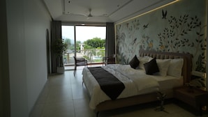 A modern bedroom with a large bed, ceiling fans, a balcony with a view, and a mural on the wall. - Tara Sitara Luxury Villas (Igatpuri)