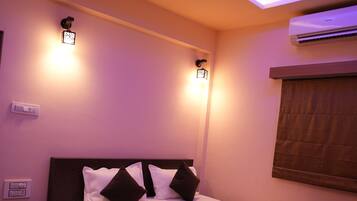 A bedroom with a bed, bedside tables, an air conditioning unit, and a ceiling fan.