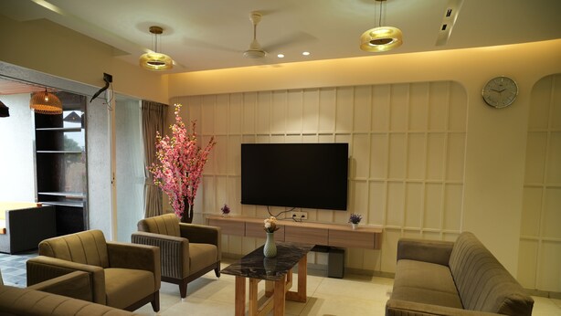 A modern living room with a flat-screen TV, comfortable sofas, a coffee table, and a decorative plant. - Tara Sitara Luxury Villas (Igatpuri)
