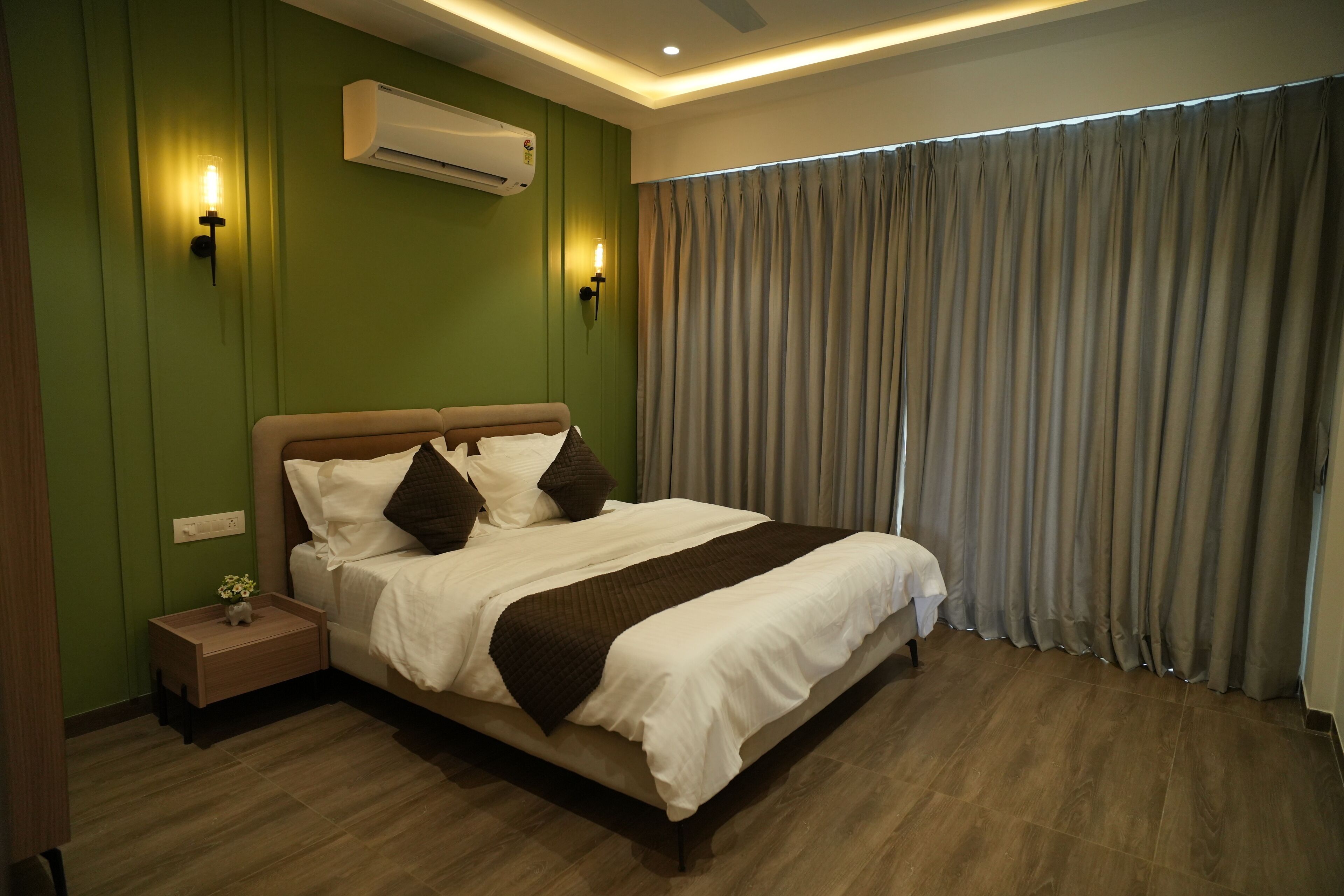 A neatly arranged bedroom with a bed, bedside tables, and an air conditioning unit.