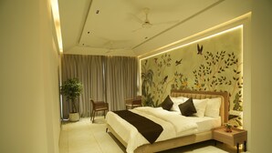 A modern bedroom with a large bed, a nightstand, a chair, and a potted plant. - Tara Sitara Luxury Villas (Igatpuri)