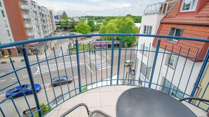 A balcony with a view of a street, buildings, and trees. - RentPlanet - Apartament Towarowa (Kolobrzeg)