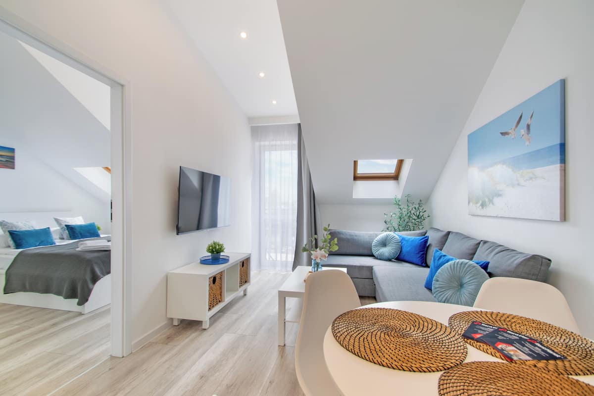 A modern living room with a sofa, a TV, and a dining area.