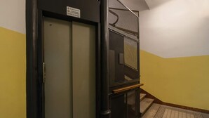 Un corridoio con una porta, una scala con ringhiera in metallo e un tappeto decorato.